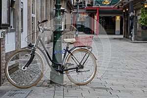 Selective focus view at bicycle lock on street lighting pole on the sidewalk with blur background of empty walking street.