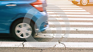 Selective focus view of the pedestrian white line crosswalk on the road motion blur of car
