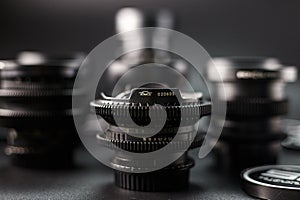 Selective focus on a vintage camera lens with serial number, surrounded by blur of other lenses, photography equipment