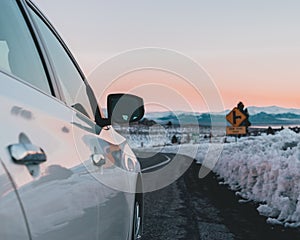 Selective focus of a white car& x27;s front side mirror parked on a road in a snow-covered area