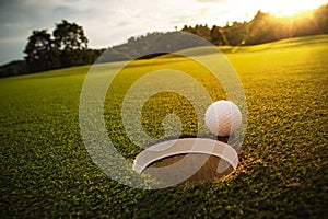 Selective focus. white golf ball near hole on green grass good f