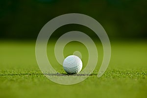 Selective focus. white golf ball near hole on green grass good f
