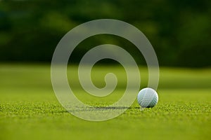 Selective focus. white golf ball near hole on green grass good f