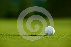 Selective focus. white golf ball near hole on green grass good f