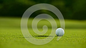 Selective focus. white golf ball near hole on green grass good f