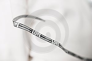 selective focus white tulle fabric with framed edges with black braid with the inscription love. creative veil for the bride