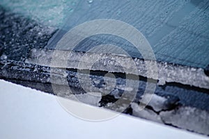 Selective focus, windshield wiper of a car covered with snow ice. Winter concept