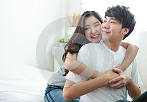 Selective focus on woman face with portrait of young asian couple girl piggyback man from back on bed,romantic asia people in love