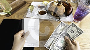 woman hand as receipt bill food and drink for payment by cash of dollar in the restaurant