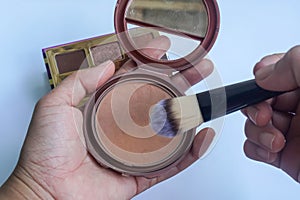 selective focus woman hand hold bronzer for make up in the morning
