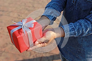 Selective focus of Woman hand holding gift box with red ribbon for Christmas and New Year`s Day or Greeting season