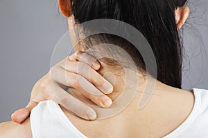 Selective focus woman with neck pain.Acute pain in a female nape holding hand to spot of Behind the scruff.health care concept