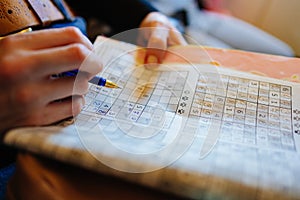 Selective focus.woman& x27;s hand with pen writes numbers into mathematical crossword