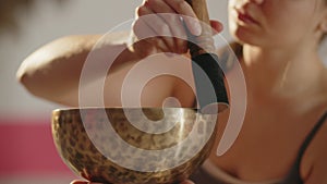 Selective focus of a woman using Tibetan singing bowl. Cropped view of a girl cleaning chakra with resting bell. Mental