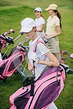 selective focus of women in caps with golf equipment