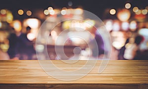 Selective focus.Wood table top with blur light bokeh in dark night cafe,restaurant background