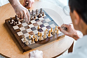 Selective focus of wooden chess board with retired men playing chess