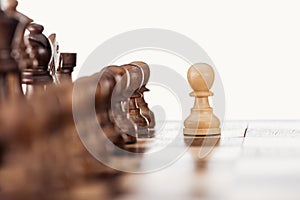Selective focus of wooden chessboard with chess figures and pawn in front isolated on white.