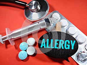 Selective focus.Word ALLERGY on wooden board with syringe,medicine and stethoscope on red background.Medical concept.