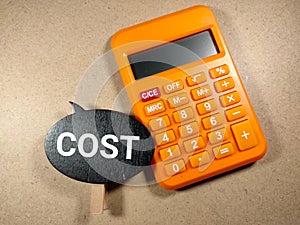 Selective focus.Word COST on wooden board with calculator on wooden background.Business concept