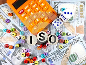 Selective focus.Word ISO on a block cylinder with calculator,dice and colorful word on a fake dolar money.Business concept idea.