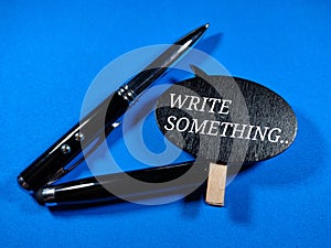 Selective focus.Word WRITE SOMETHING on wooden board with pen on blue background.Business concept