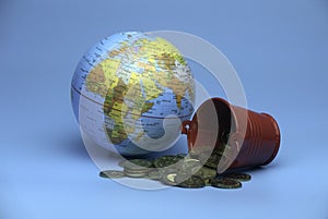 Selective focus of world globe and a red bucket with a gold coins isolated on a blue background. Business and finance concept