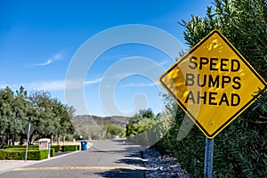 Selective focus on a yellow speed bump sign with a defocused road in the background.