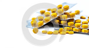 Selective focus on yellow tablets pill on blurred background of blister pack of round yellow pills. Diclofenac medicine