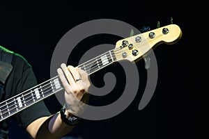 Selective focus on young Asian man bassist`s left hand playing chord on neck of electric bass solo on stage at concert