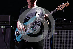 Selective focus on young Asian man bassist`s right hand performing playing electric bass solo on stage at concert