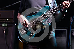 Selective focus on young Asian man bassist`s right hand performing playing electric bass solo on stage at concert