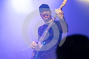 Selective focus on young Asian man bassist`s right hand performing playing electric bass solo on stage at concert