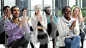 Selective focus of young businesswoman applauding together with interracial colleagues during seminar