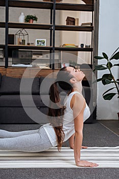 Selective focus of young woman practicing cobra pose in living room