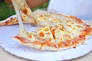 In selective fous pan of pizza with  cheese stretches between pizza and a piece photo