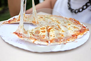 In selective fous pan of pizza with  cheese stretches between pizza and a piece photo