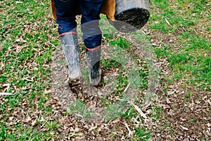 Selective of a person in muddy welly boots walking on green grass