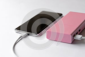 Selective soft focus photo of charging smart phone via pink color power bank