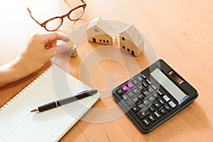 Selectove focus of Stack of money coin for saving for home, property with small wood house and calculator on the background.