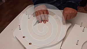 Self-assembly of furniture. A man installs cams in the wooden elements of a tabletop shelf