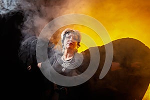 Self-assured adult blonde middle age woman with black angel wings. Model posing in studio on black background. Dangerous