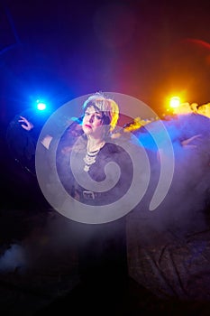 Self-assured adult blonde middle age woman with black angel wings. Model posing in studio on black background. Dangerous