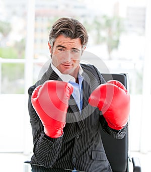 Self-assured businessman wearing boxing gloves photo