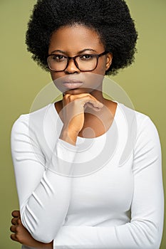 Self assured intelligent African American woman in glasses looking at camera with strict glance.