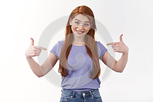 Self-assured smiling caucasian woman with long red hair talking personal achivement, pointing herself at chest and