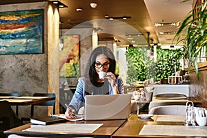 Self-belief and hard work will always earn you success. Young beautiful businesswoman drinking coffee, writing in