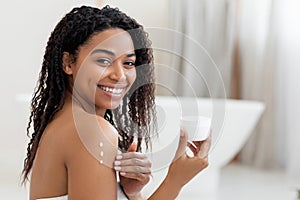 Self-Care Concept. Young Black Woman Applying Moisturising Body Lotion On Skin