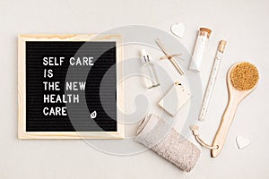 Self care is the new health care. Motivational quote on black letter board with variety of organic body and face care