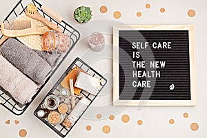 Self care is the new health care. Motivational quote on black letter board with variety of organic body and face care photo
